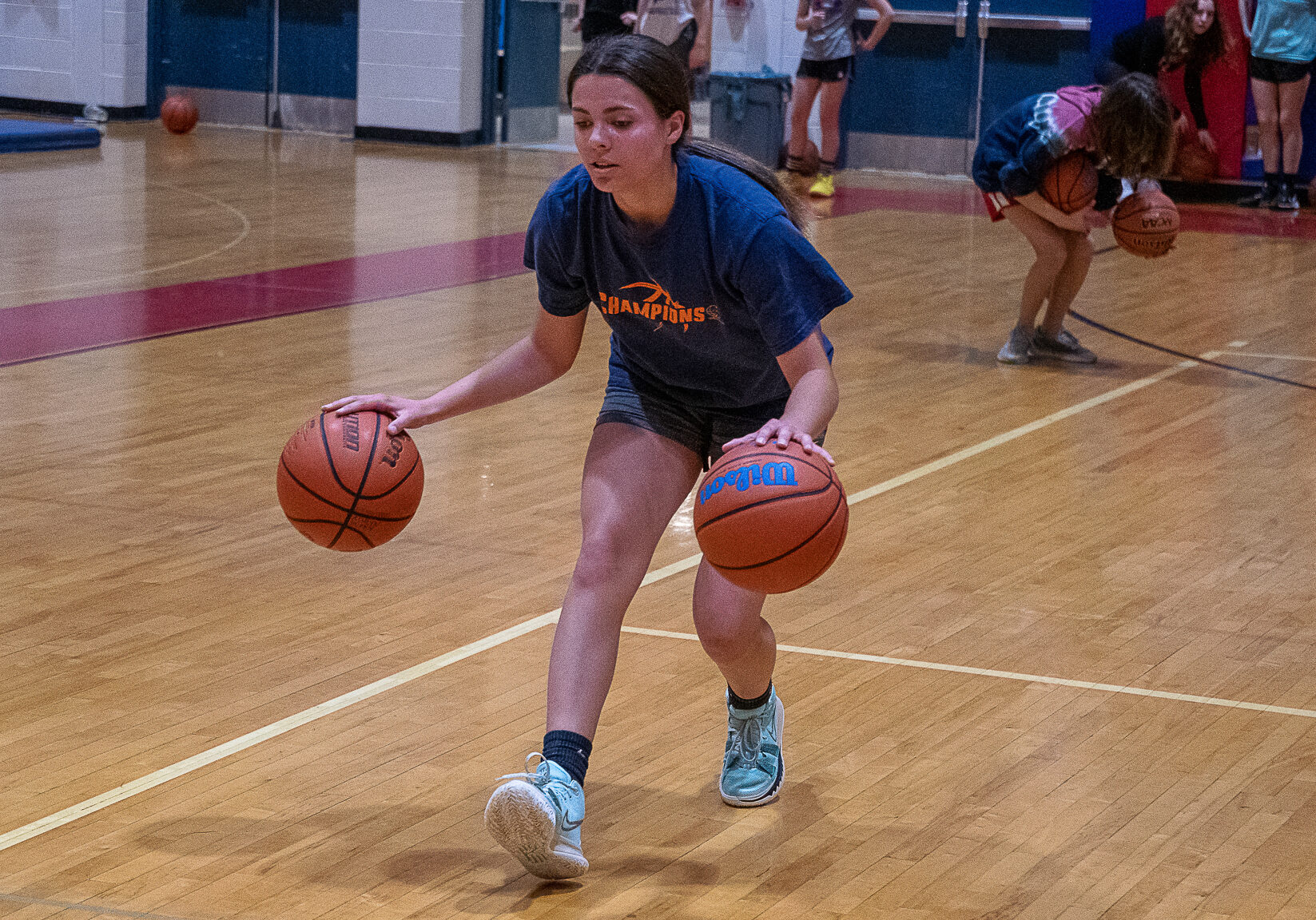Girl dribbling two basketballs
